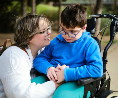 Disabled boy in a wheelchair enjoying a walk outdoors with his mother.